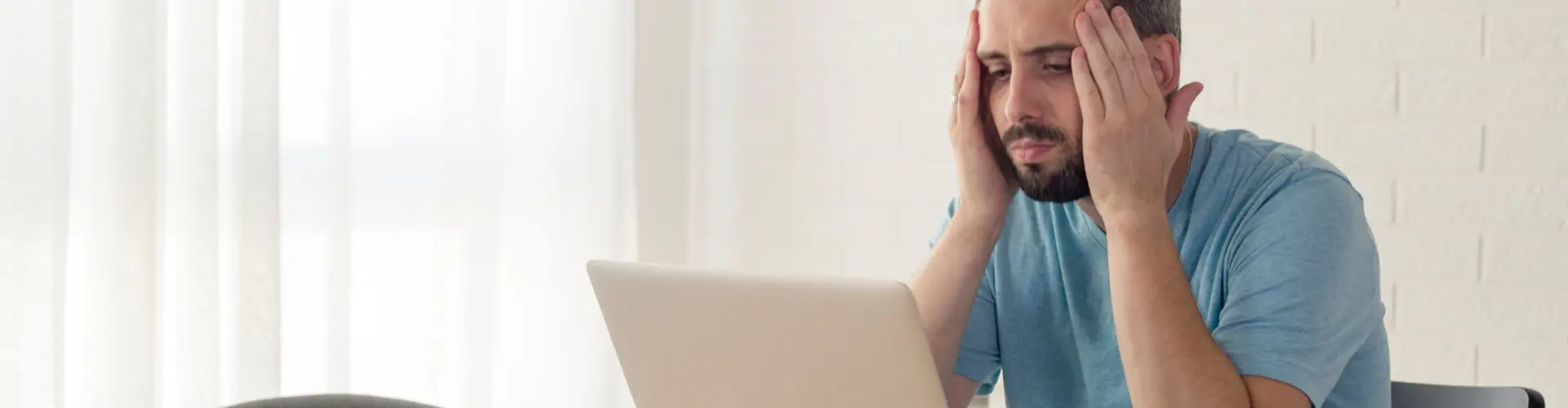 Ein junger Mann arbeitet enttäuscht an seinem Laptop