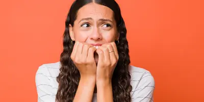 Frau hat Angst und hält sich die Hände vor den Bund