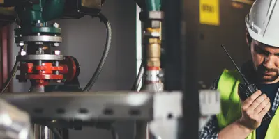 Ein Ingenieur prüft seine Pläne und spricht in ein Funkgerät