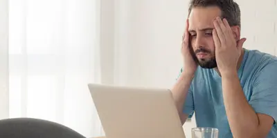 Ein junger Mann arbeitet enttäuscht an seinem Laptop