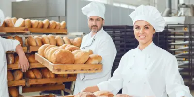 Eine Gruppe von Bäckern halten lachend frische Brote in der Hand