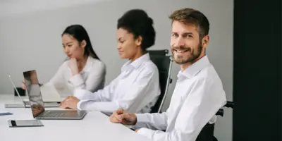 Ein Mann und zwei Frauen sitzen am Tisch vor einem Laptop