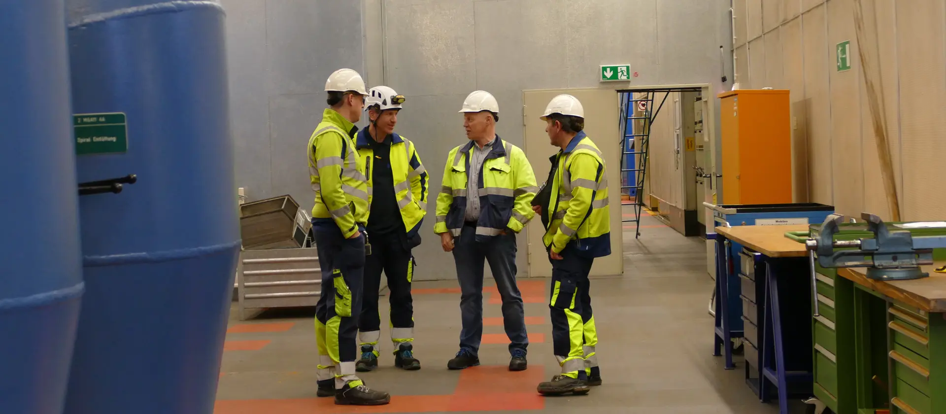Fachkräfte in Schutzkleidung bei einer Teambesprechung in der Industriefertigung.