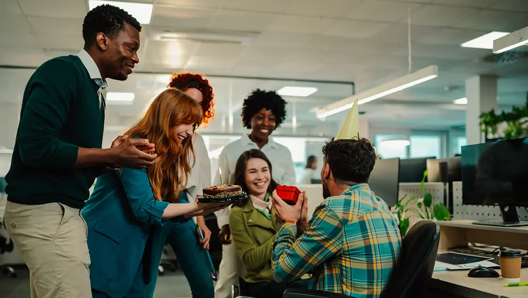 Arbeitskollegen überreichen einen Kuchen und ein Geschenk
