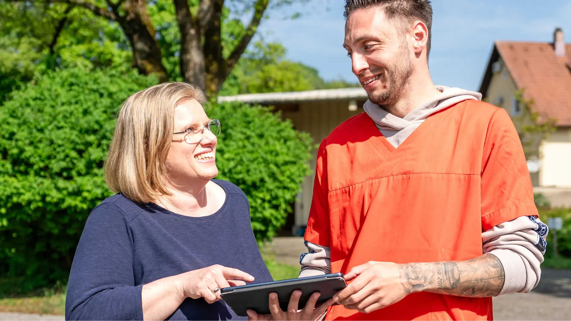 Zwei Arbeitskollegen im Gespräch mit einem Tablet in der Hand